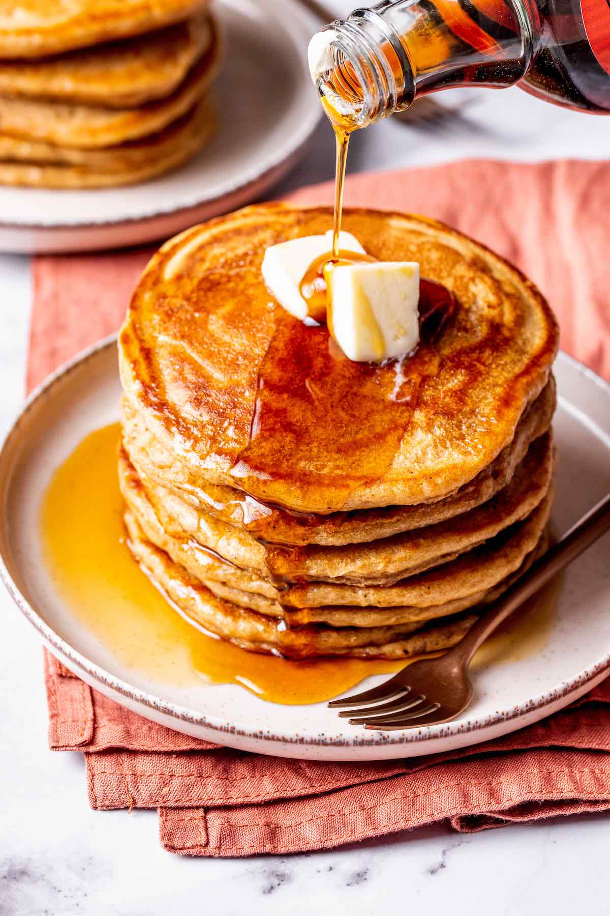 fluffy oat milk pancakes with maple syrup on top.