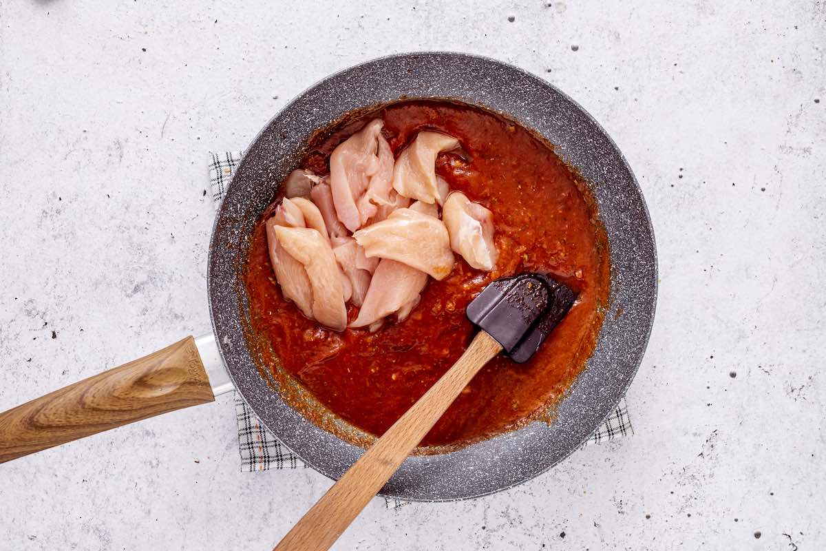 adding raw chicken to tinga sauce.