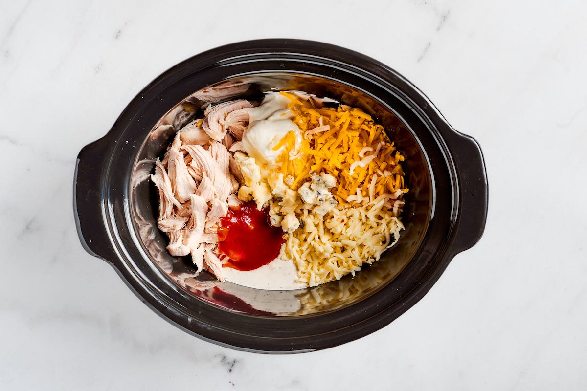 shredded chicken, whipped cottage cheese, buffalo sauce, blue cheese, and cheddar cheese in a slow cooker.