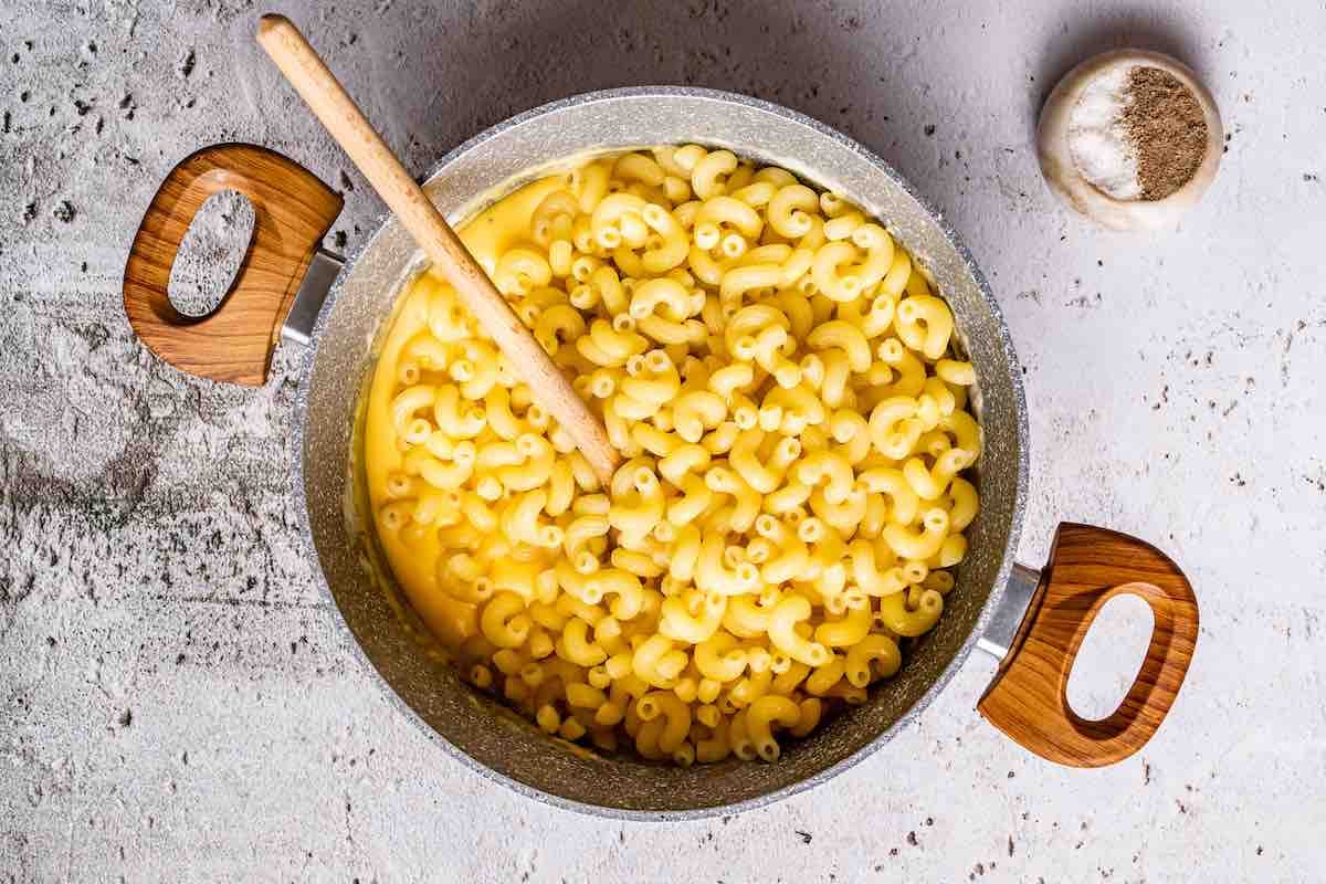 folding in keto macaroni noodles into a pot of cheese sauce.