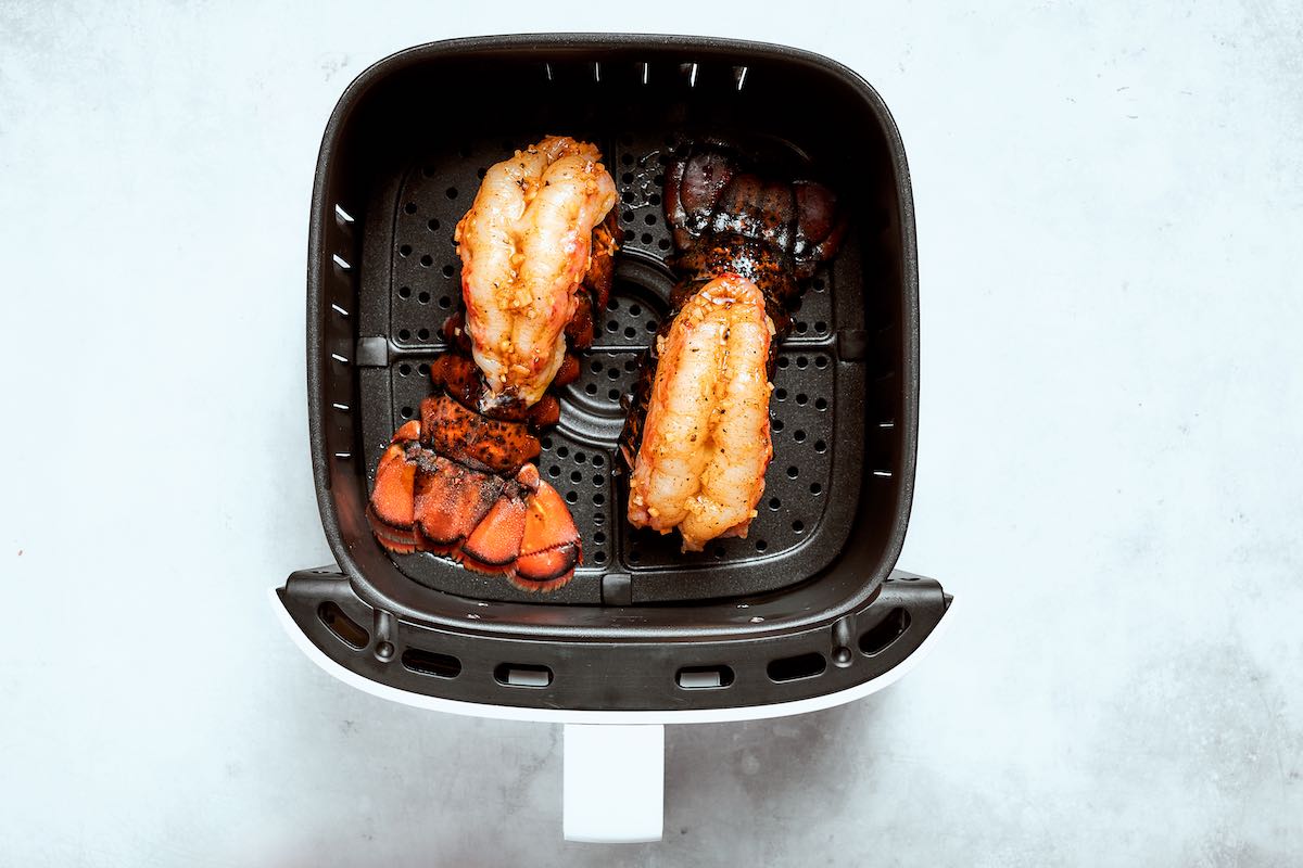 two seasoned raw lobster tails in the air fryer. 