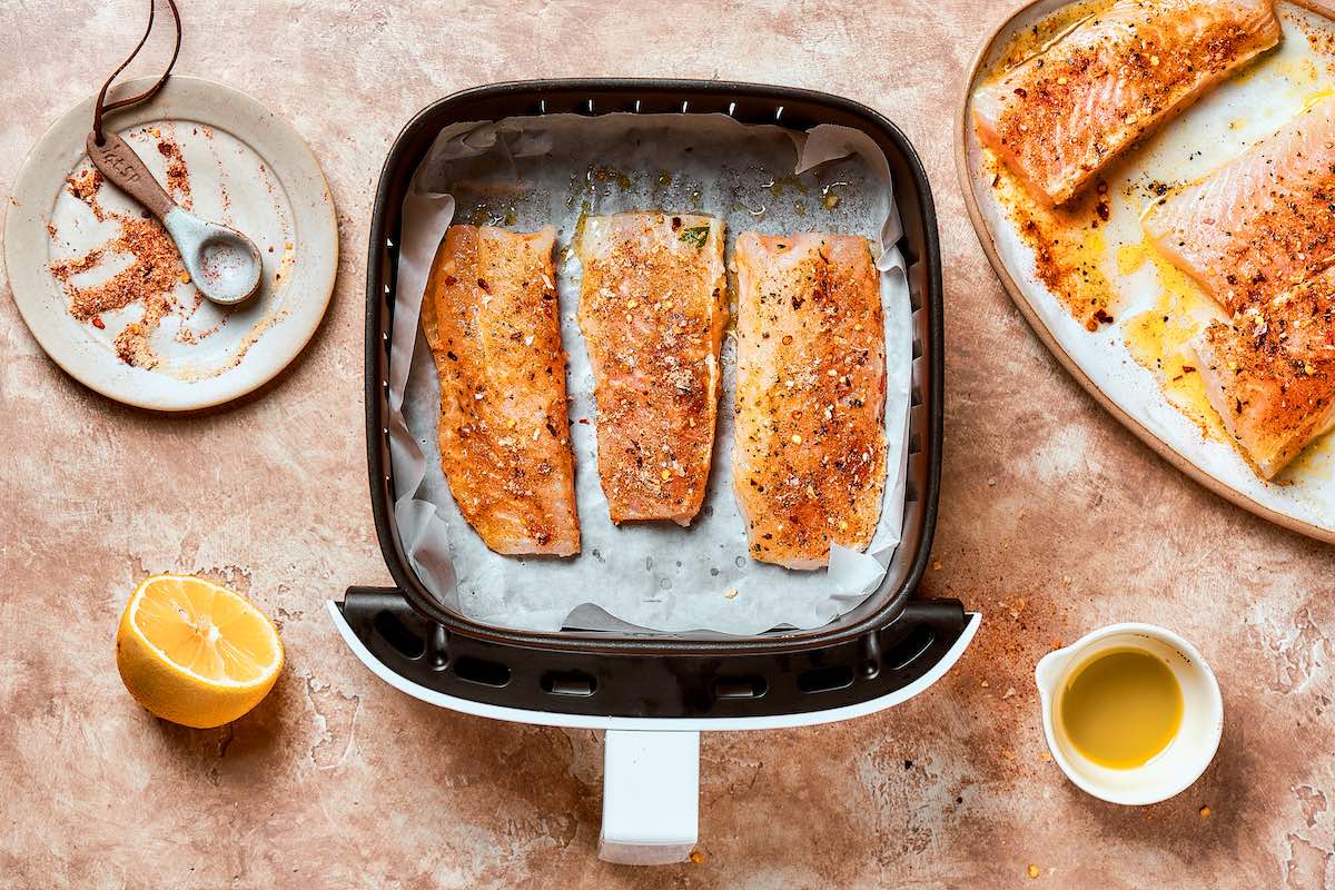 seasoned raw flounder in the air fryer basket.