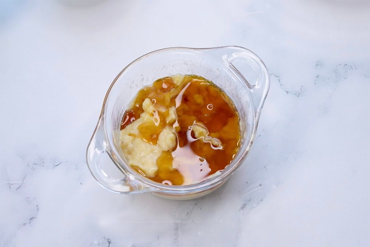 banana, maple syrup, coconut oil, and eggs in a bowl.