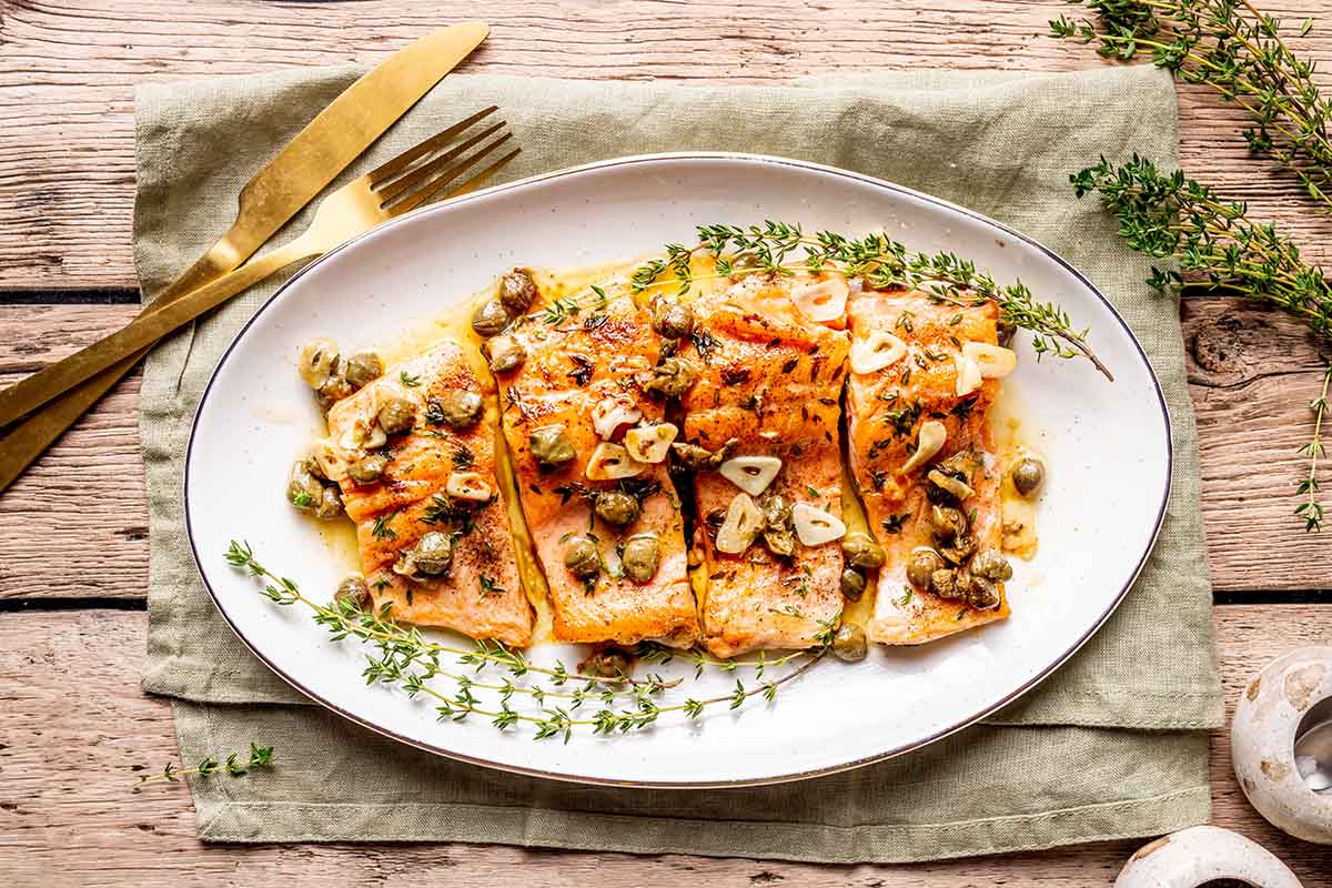 serving dish with steelhead trout fillets and fresh herbs.