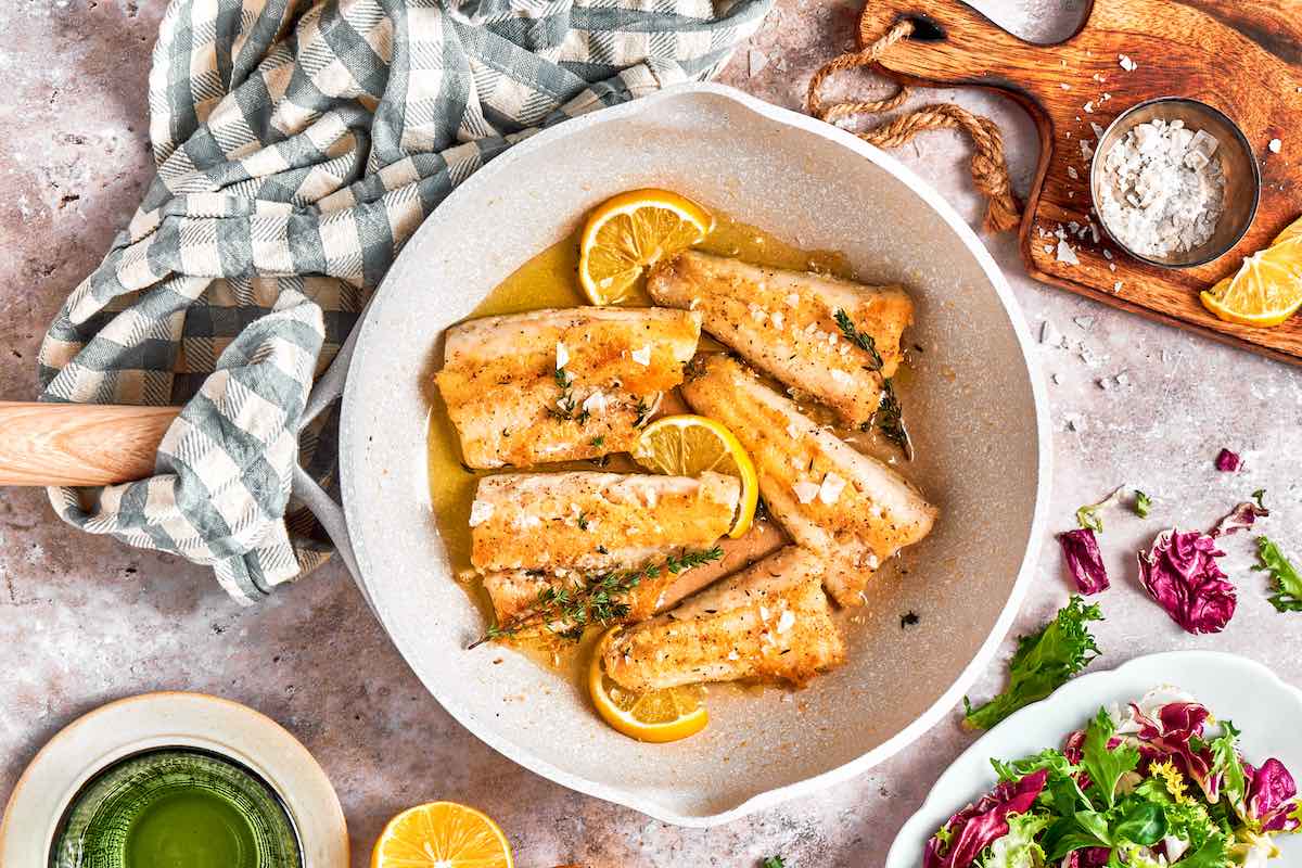 pan seared perch fillets in a skillet with fresh lemon juice and a sprig of dill.