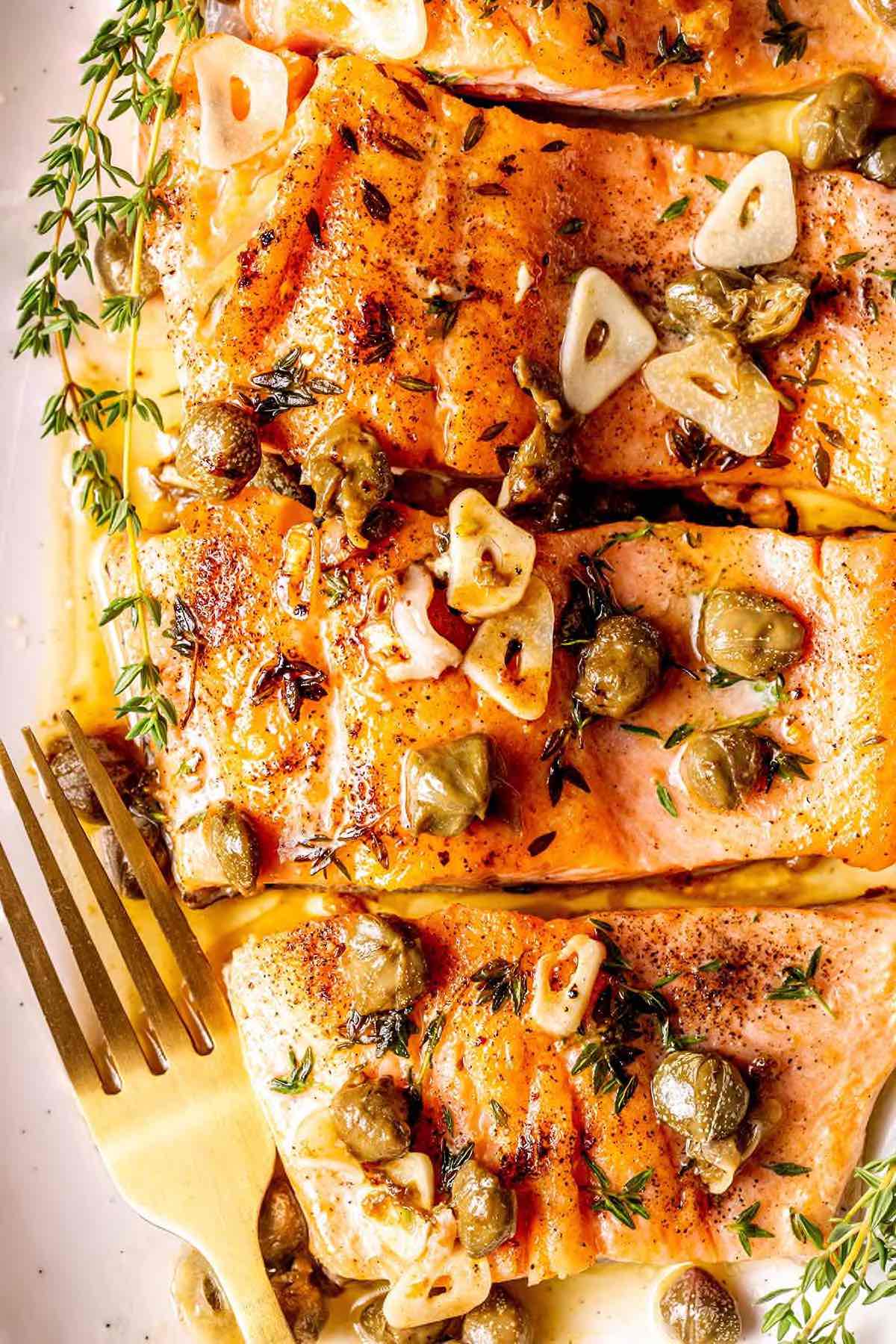 steelhead trout with lemon caper garlic sauce on a plate.