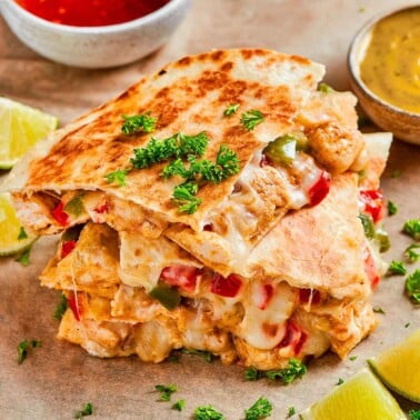 air fryer quesadillas recipe featuring a stack of quesadillas with fresh herbs on top.