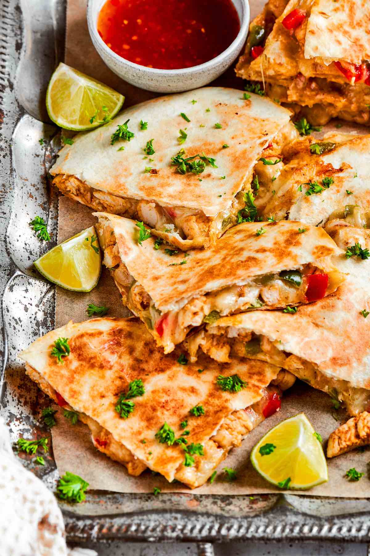 air fryer quesadillas on a baking tray with fresh limes and salsa.