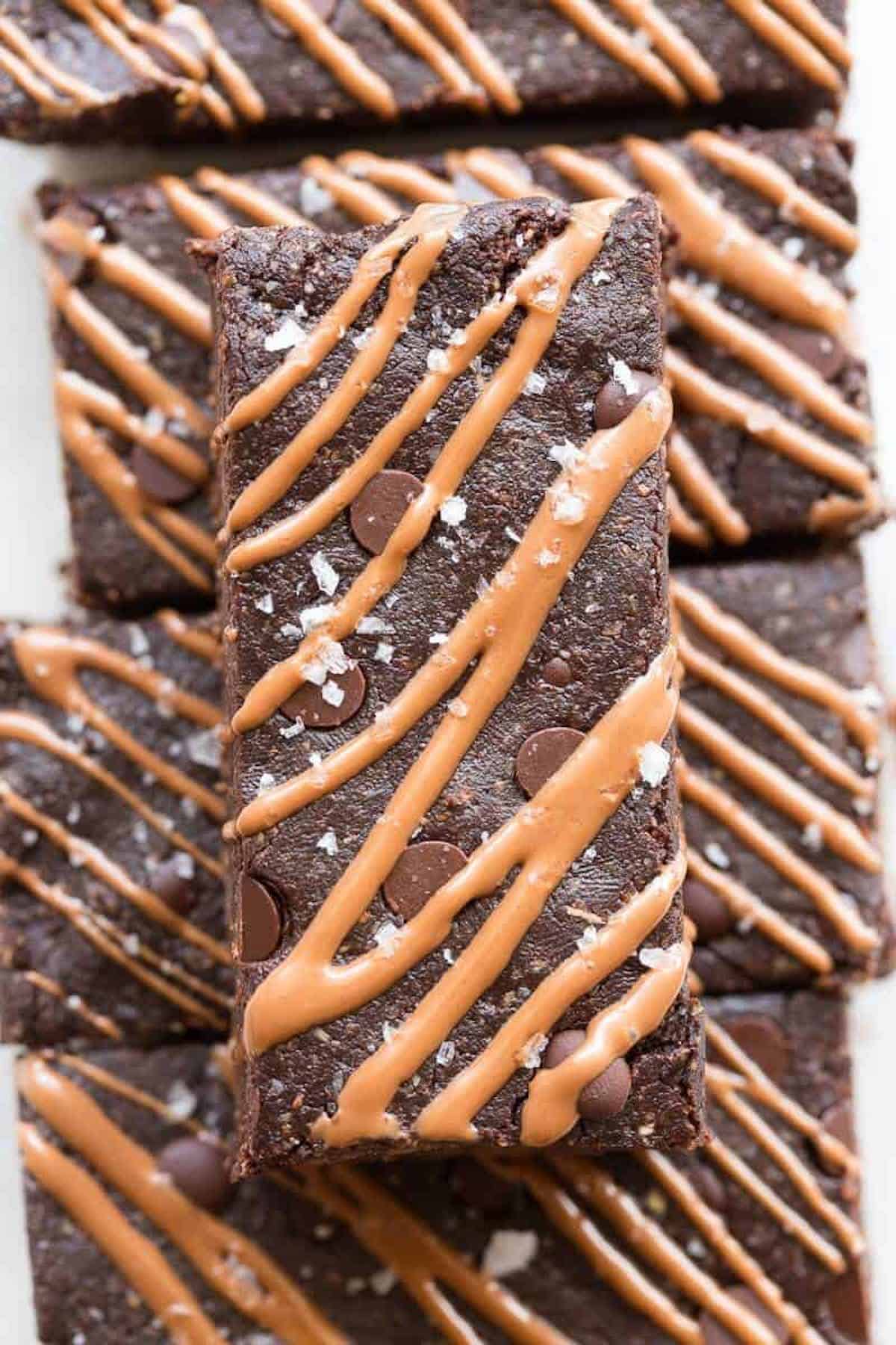 Chocolate protein bars cut into rectangles with sea salt and chocolate drizzle on parchment paper. 