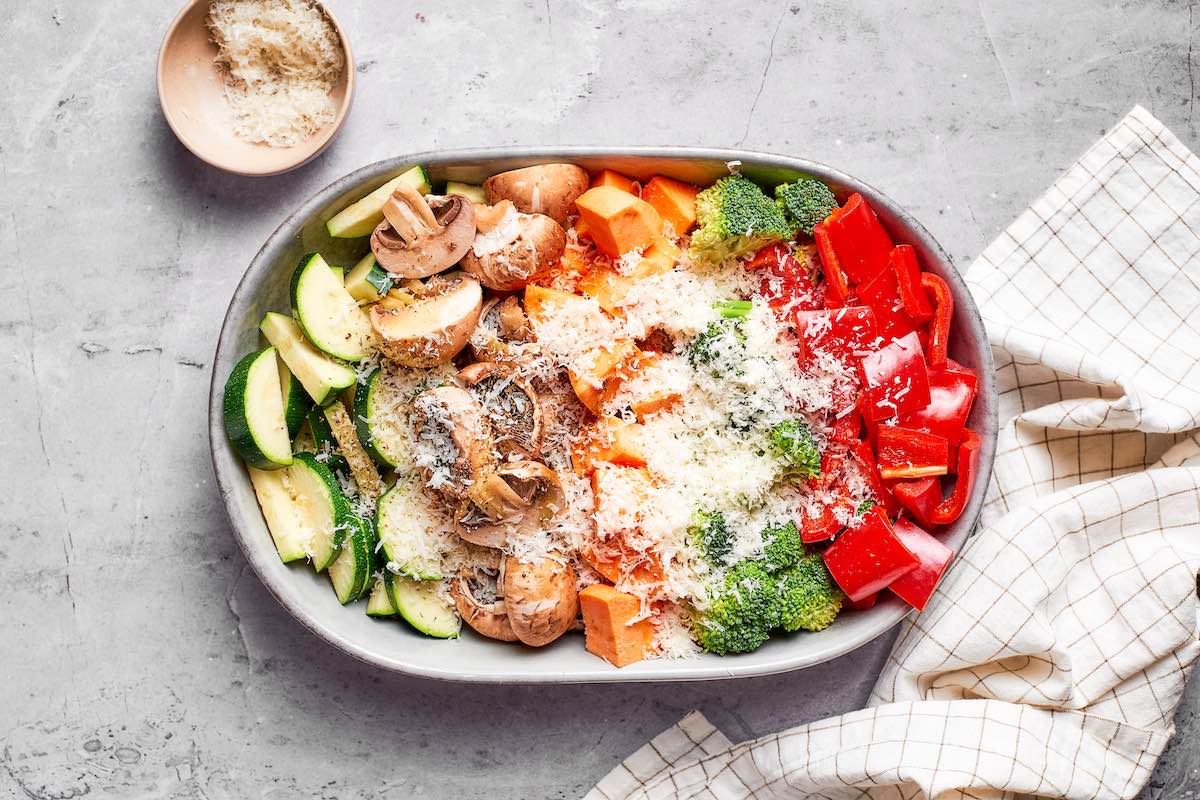 Raw air fryer vegetables with zucchini, mushrooms, sweet potato, broccoli, and red bell pepper topped with freshly grated Parmesan cheese.