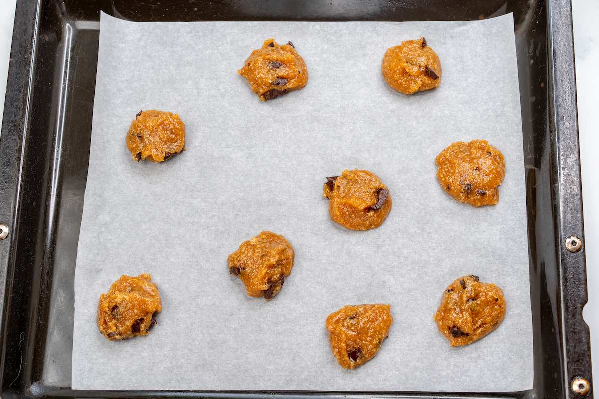 shaped unbaked almond butter cookies on parchment paper.