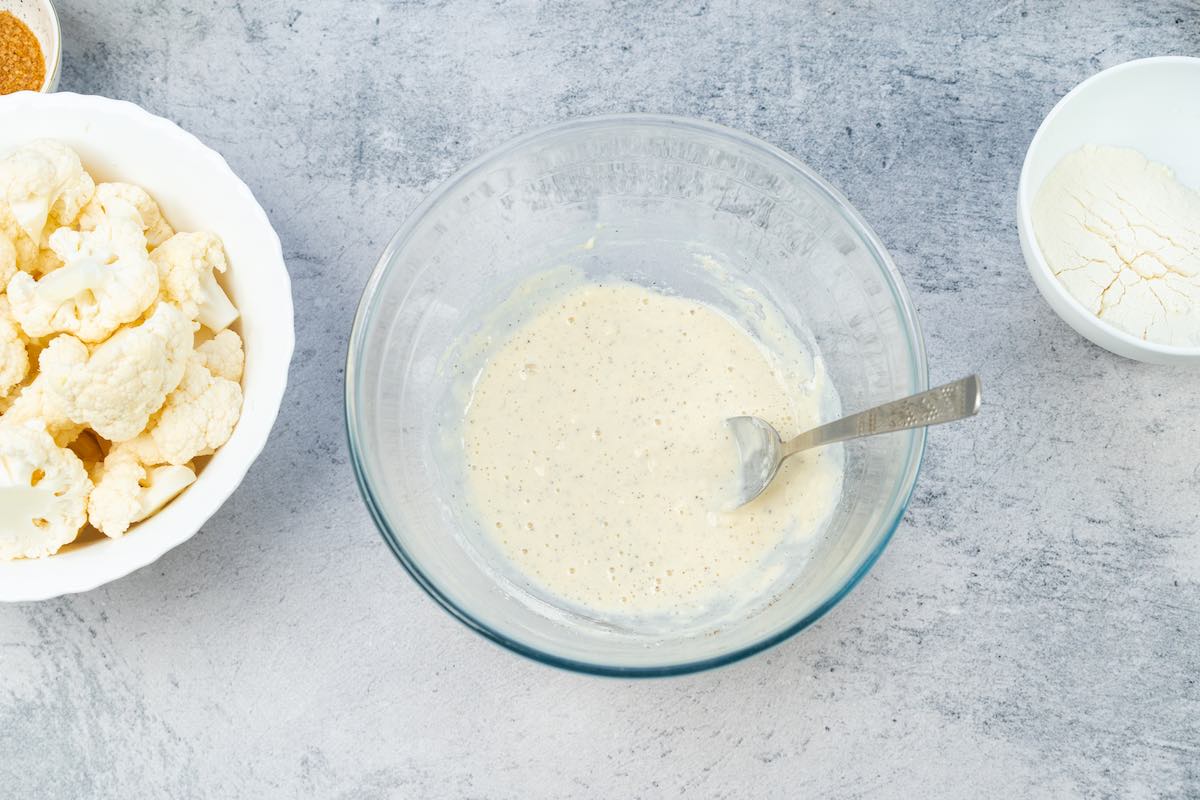 flour, milk, and seasonings in a mixing bowl for the coating of Asian cauliflower.