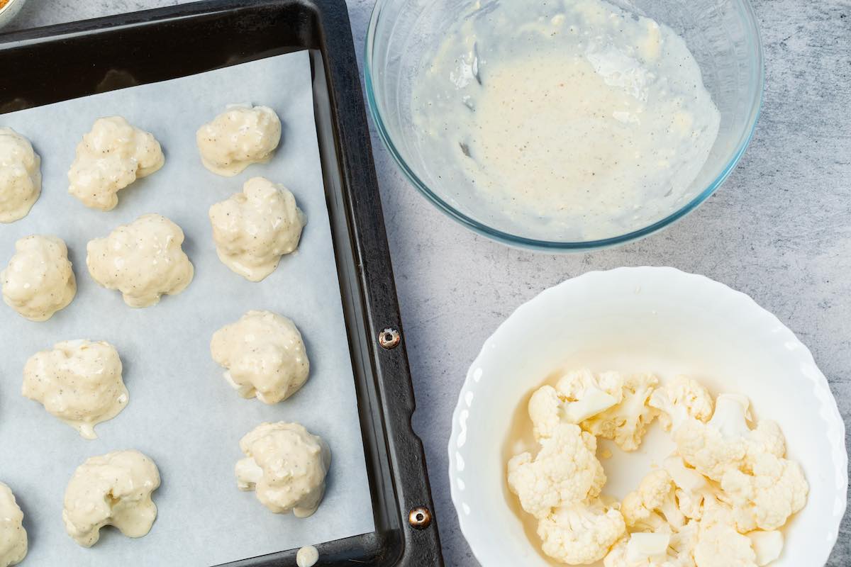 dipping raw cauliflower in batter and placing on baking sheet.