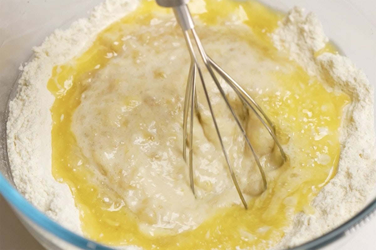 adding melted butter to blueberry banana bread batter.