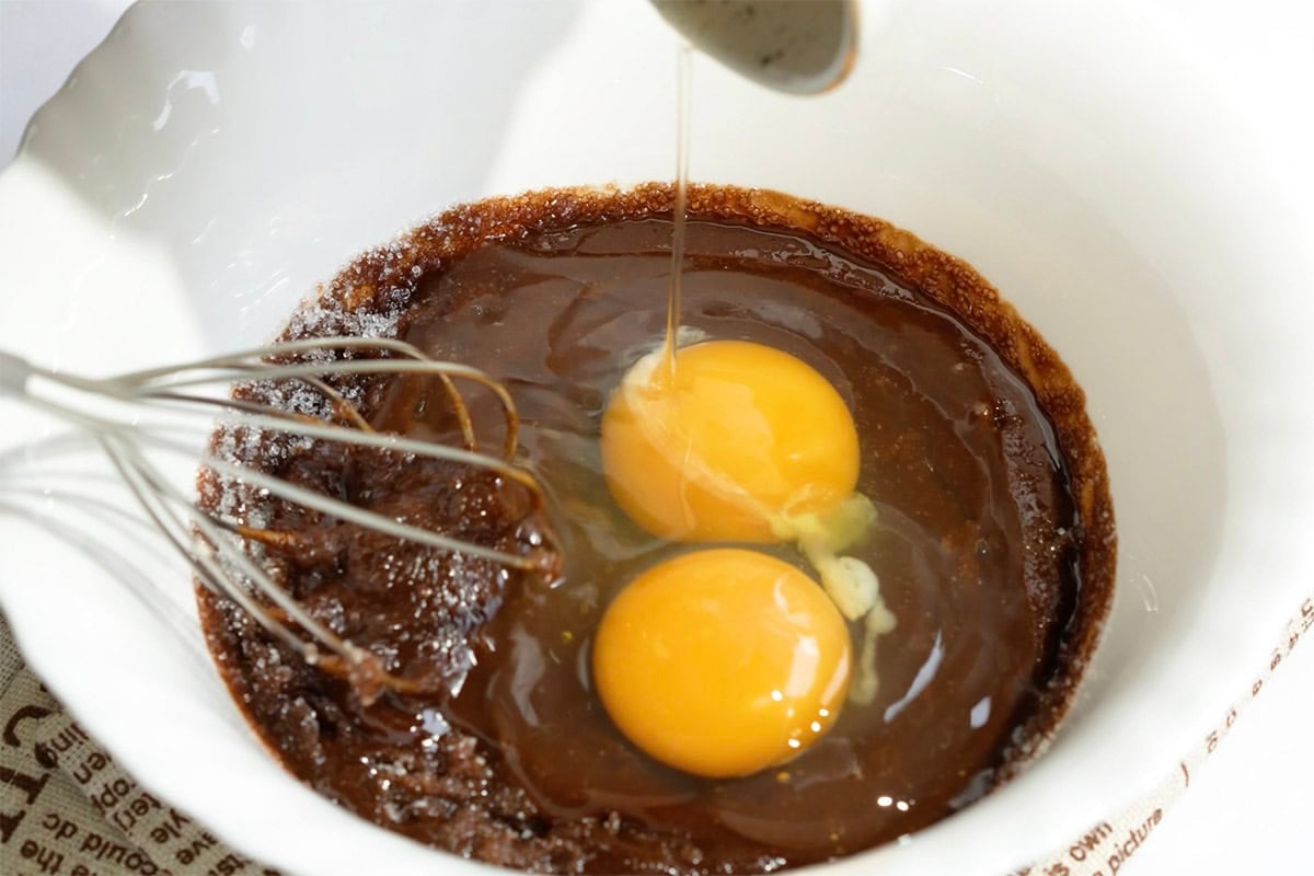 beating eggs into the melted chocolate and sugar mixture.