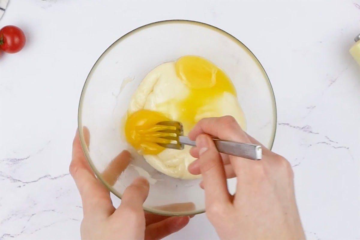 whisking melted mozzarella and egg yolks in a bowl.