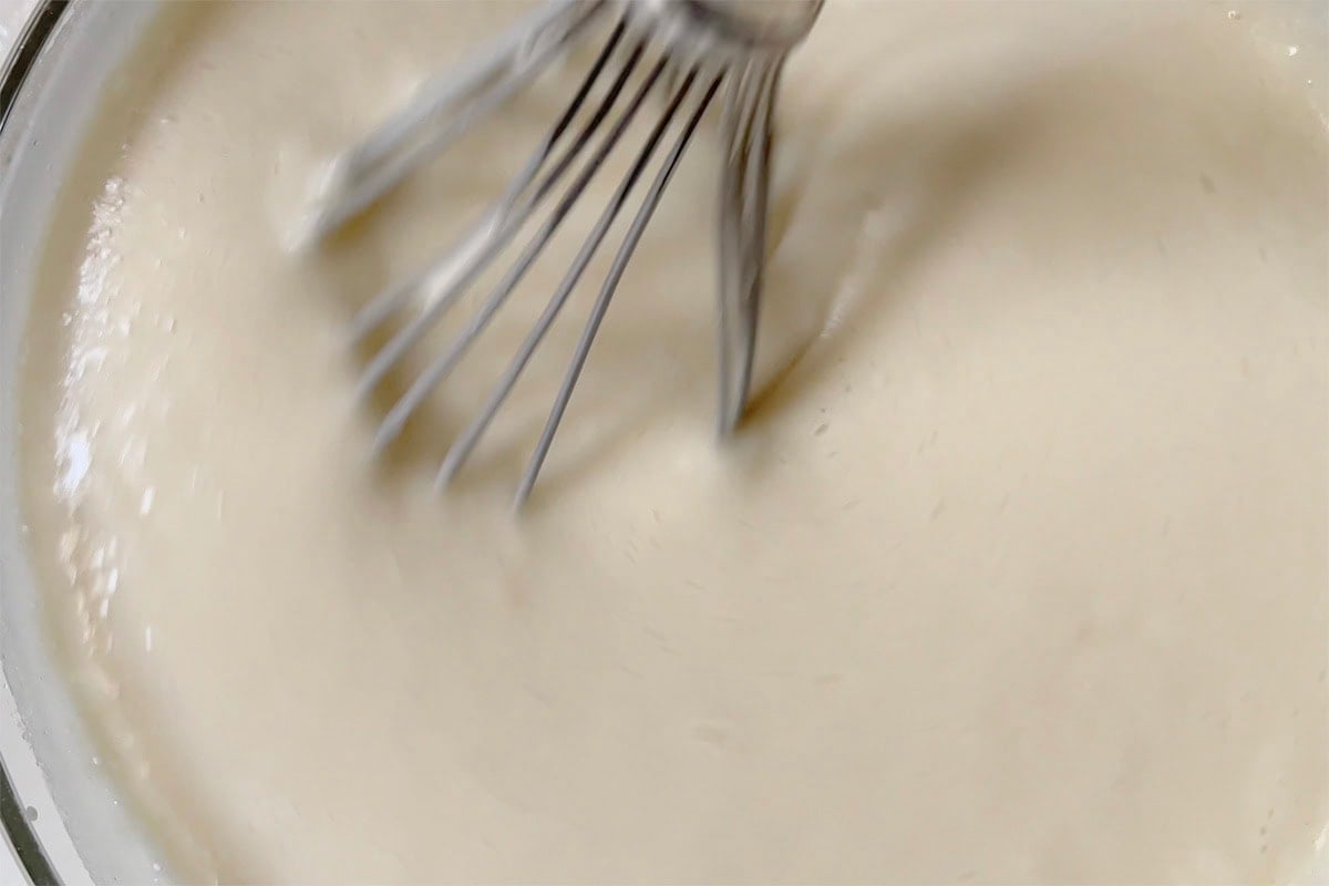 whisking the cake batter in a mixing bowl.