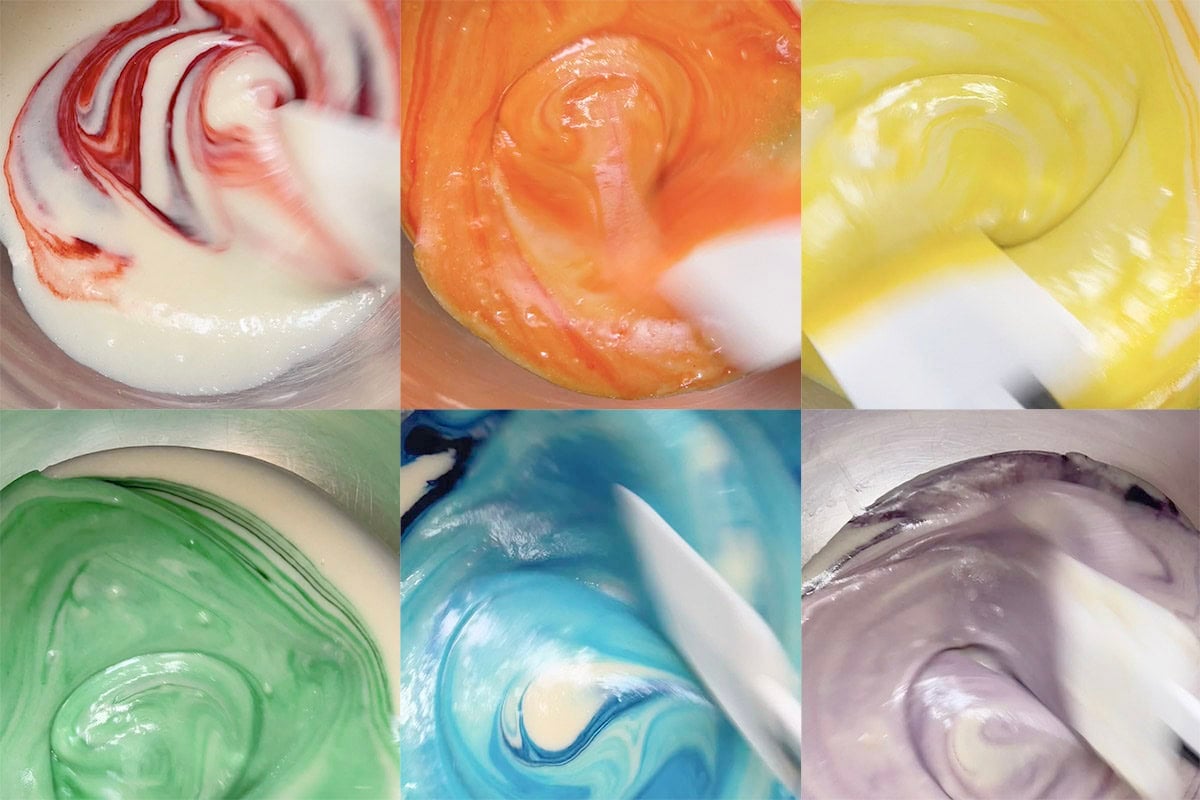 six bowls of cake batter with food gel added in- red, orange, yellow, green, blue, and purple.
