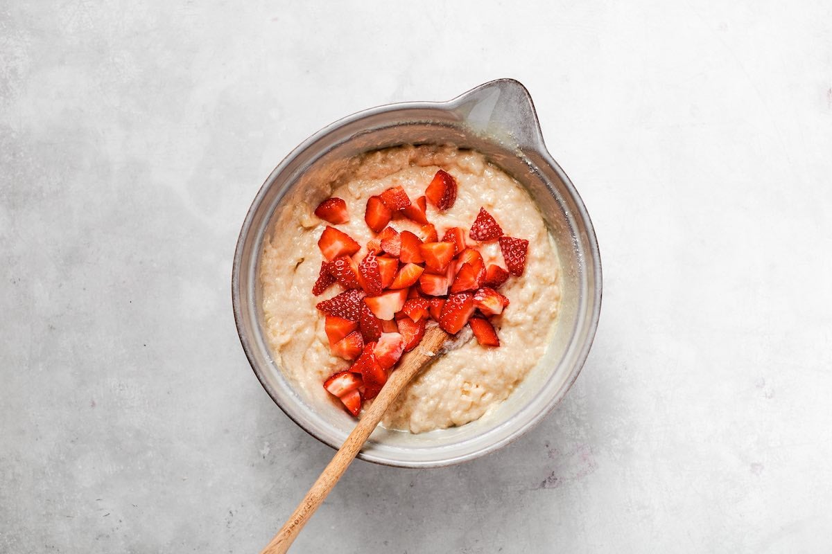 banana bread batter in a bowl with sliced strawberries mixed in.