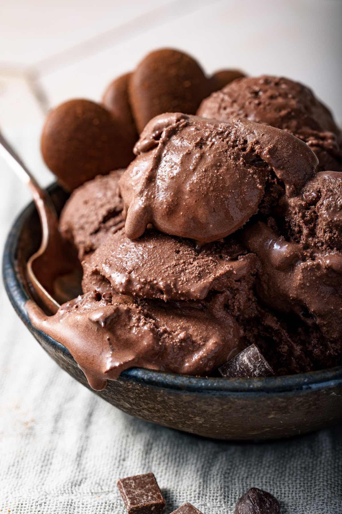 chocolate brownie ice cream in a blue bowl with a spoon in the center.