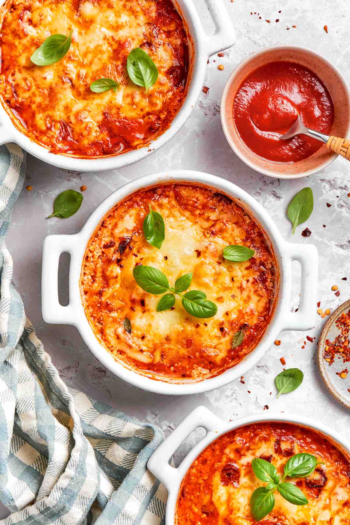 cottage cheese pizza bowls in white ramekins with fresh basil on top.