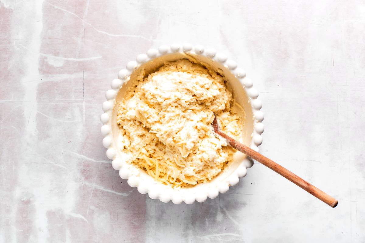 cheese, flour, and milk in a white mixing bowl.