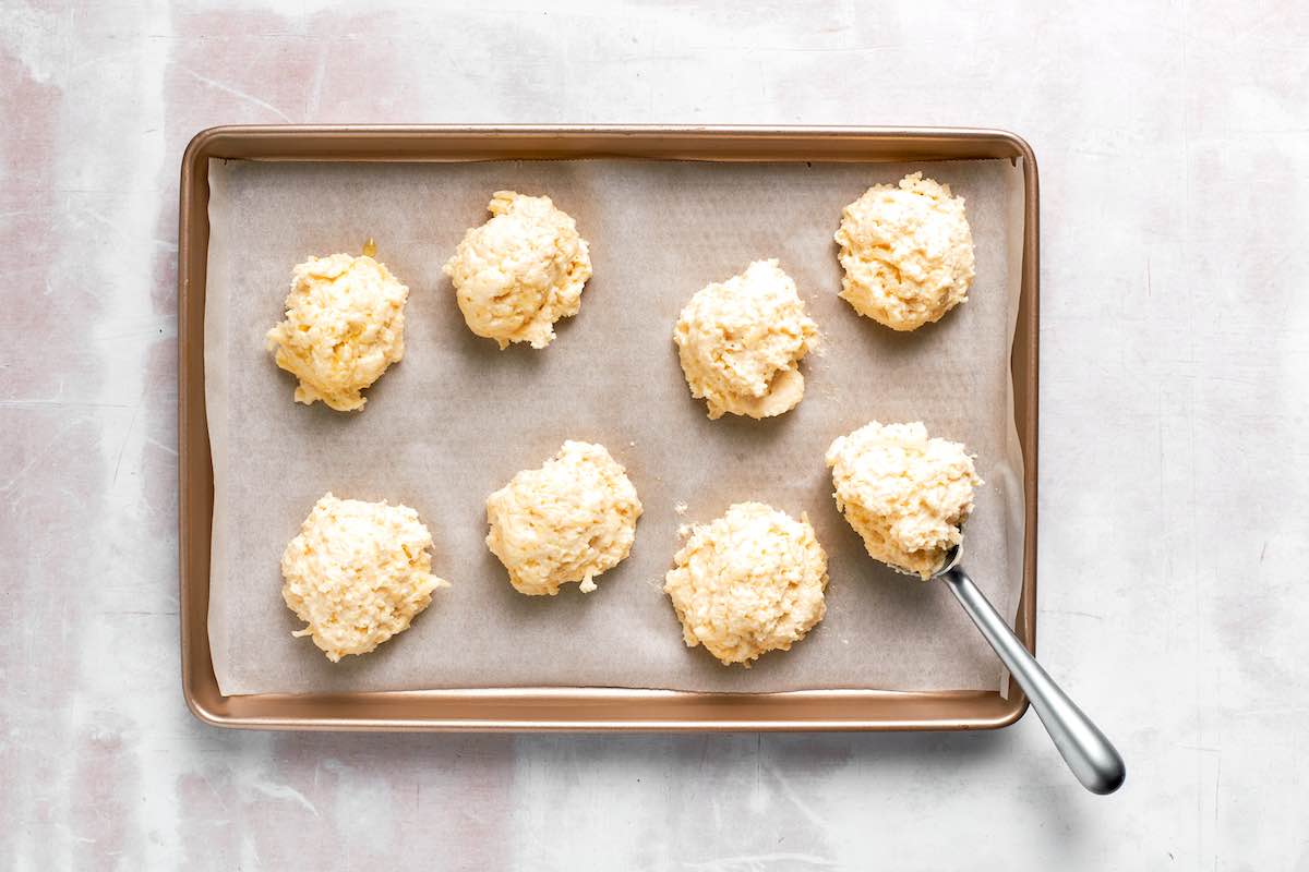 dropping breakfast biscuit dough onto a lined sheet.