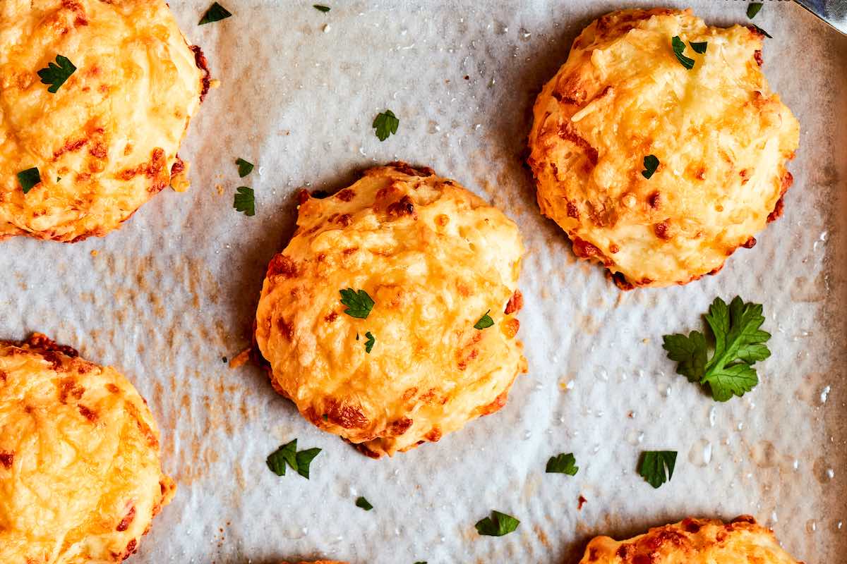 baked breakfast biscuits on a baking sheet with freshly chopped herbs on top.