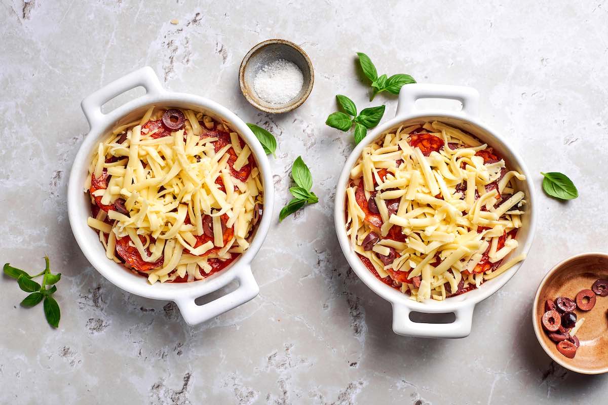 assembled cottage cheese bowls featuring layers of cottage cheese, marinara sauce, shredded cheese, pepperoni, and olives.