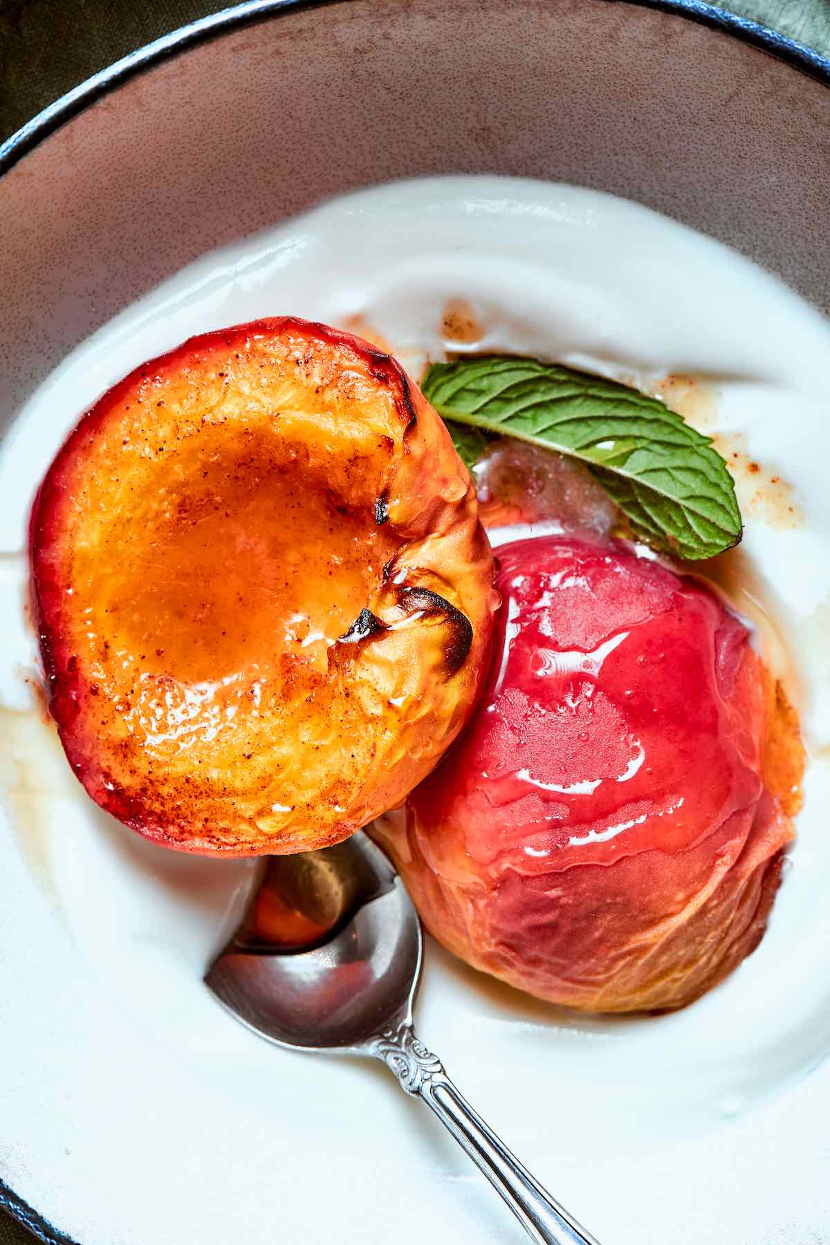 air fried peaches in a bowl of yogurt with a drizzle of honey on top.