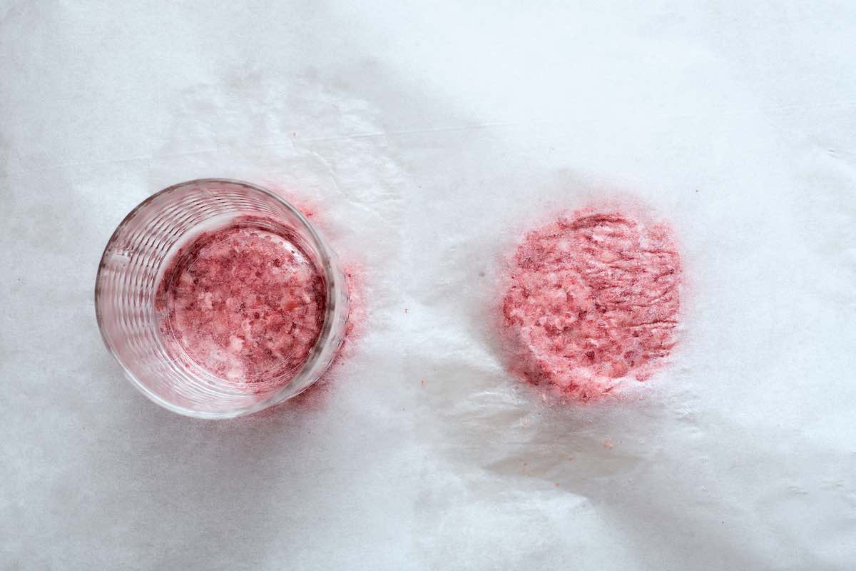 smashing beef patties between parchment paper.