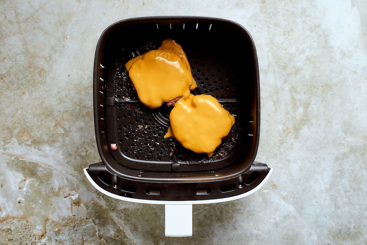 flipped smash burgers in the air fryer with cheese on top.