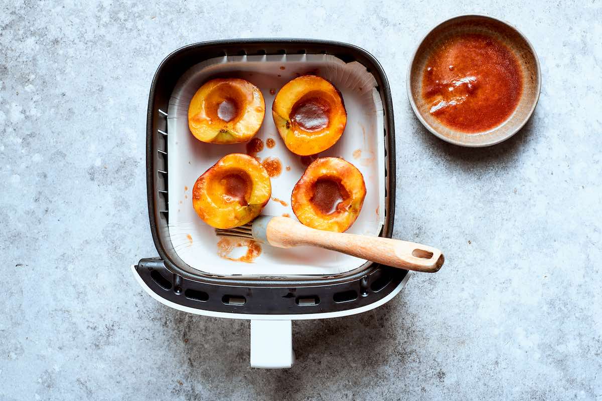 brushing peaches with brown sugar glaze in the air fryer.