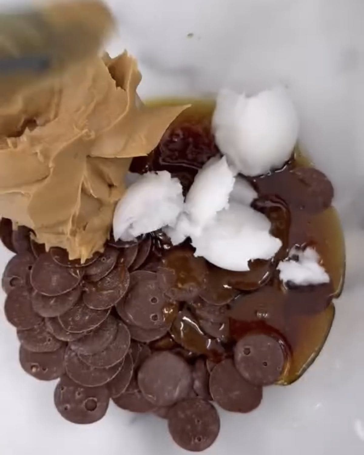 peanut butter, coconut oil, syrup, and chocolate chips in a bowl.