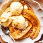 air fryer bananas recipe in a white bowl with vanilla ice cream.