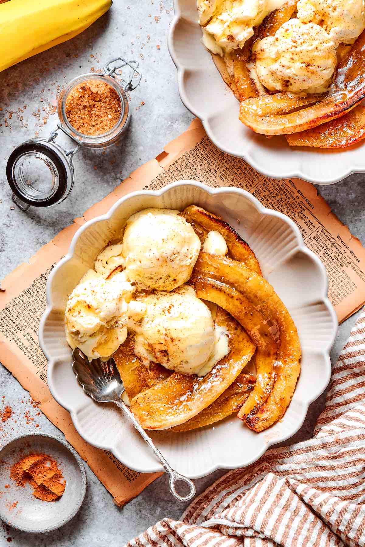 air fryer bananas in a white bowl with vanilla ice cream on top.