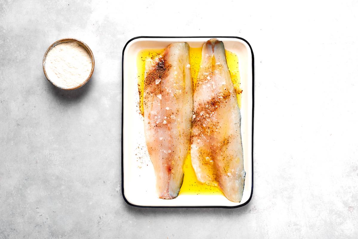 raw walleye fillets in a tray with salt, pepper, and smoked paprika.