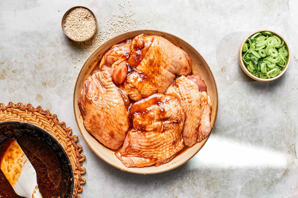 raw chicken thighs in a bowl covered in teriyaki sauce marinade.