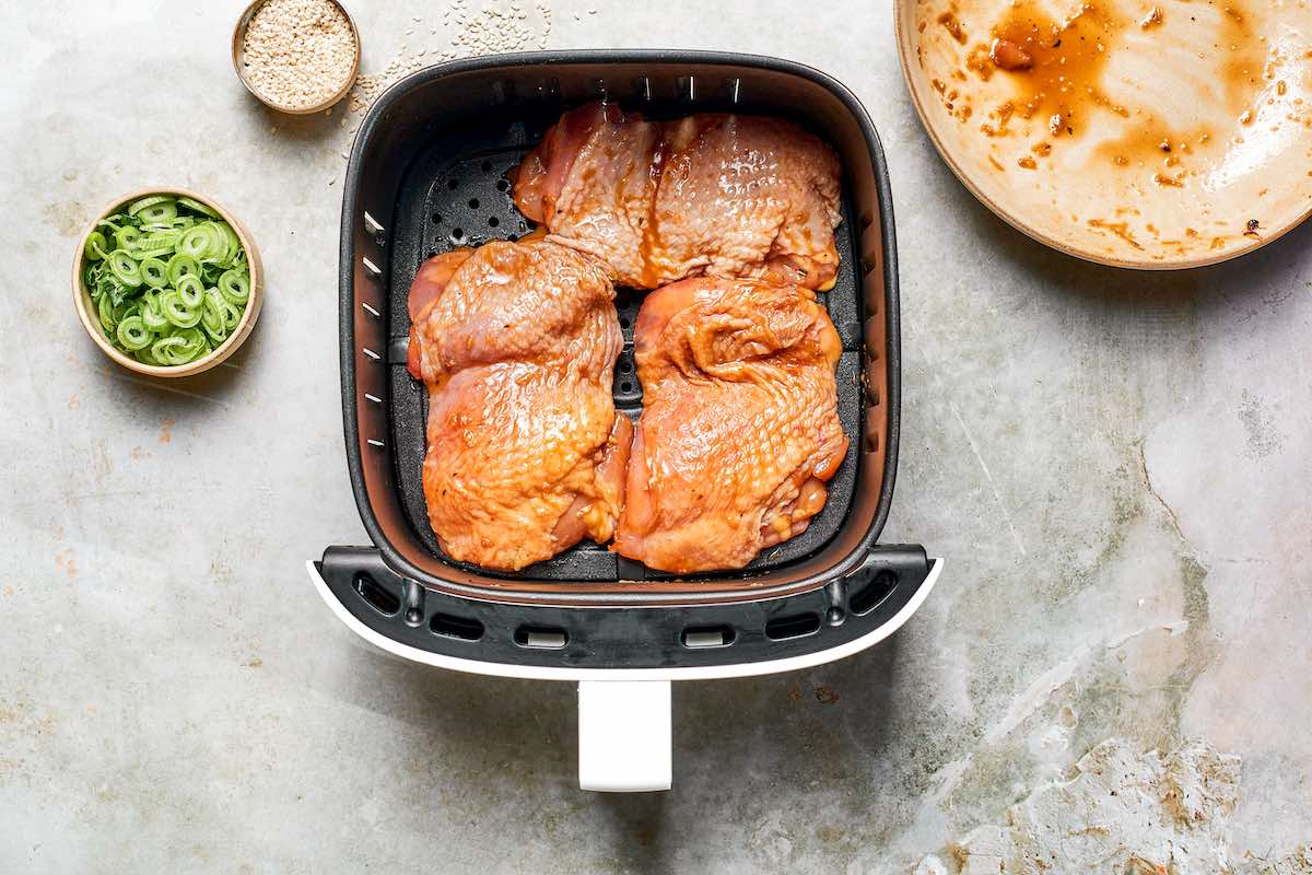 marinated raw chicken thighs in the air fryer basket.
