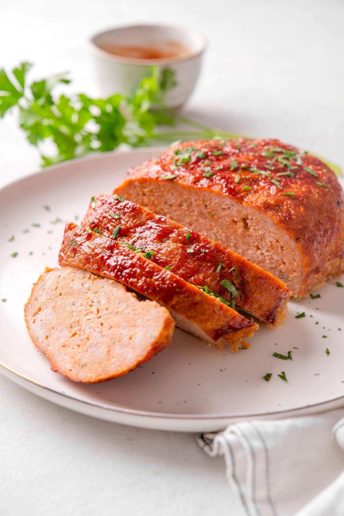 juicy turkey meatloaf sliced on a white plate.