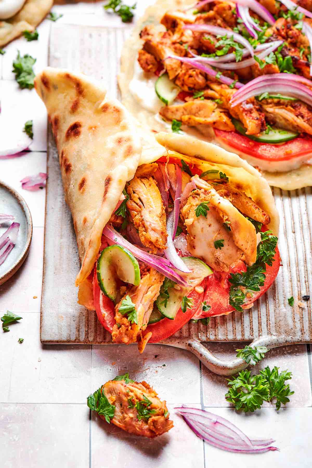 air fryer chicken shawarma in warm pita with cucumber, tomatoes, parsley, and red onion.