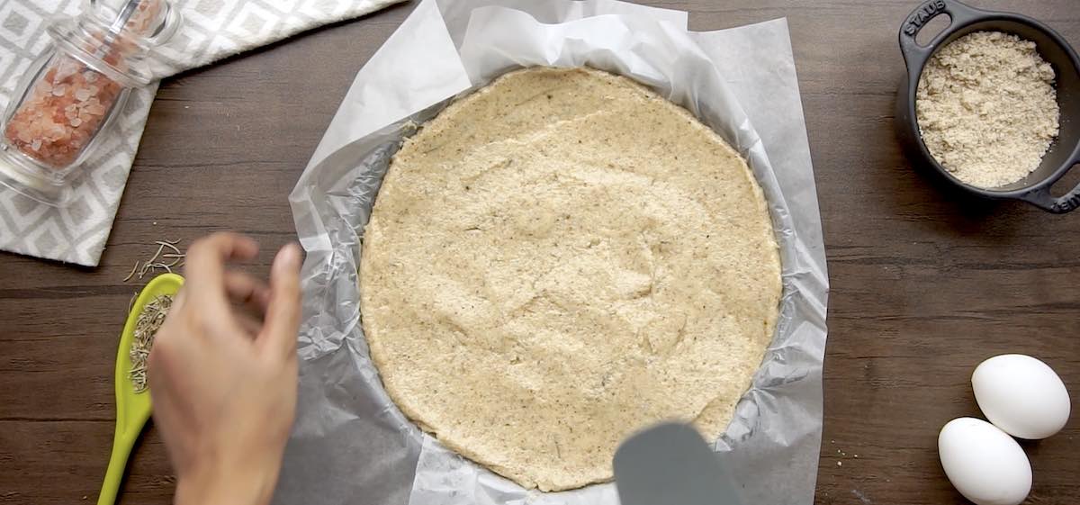 unbaked keto pizza crust on a baking sheet.