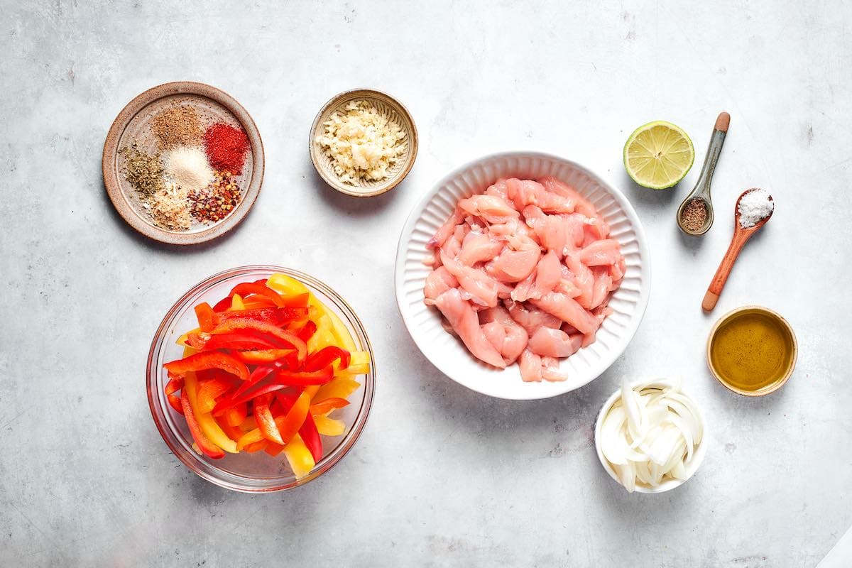sliced chicken breast and veggies in bowls, along with fajita seasoning mix.