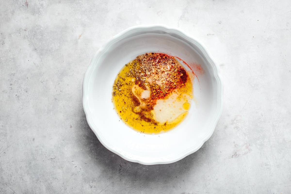 olive oil and fajita seasoning mix in a white bowl.