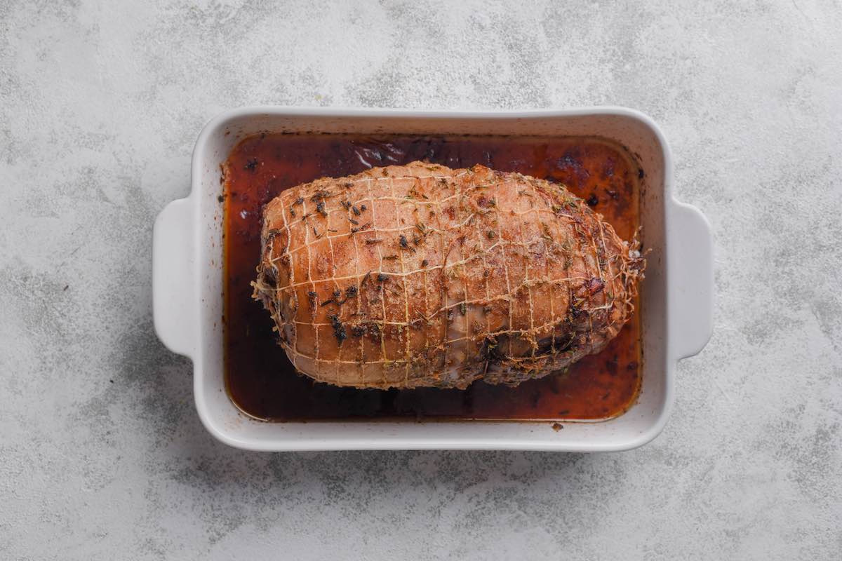 roasted leg of lamb in baking dish.