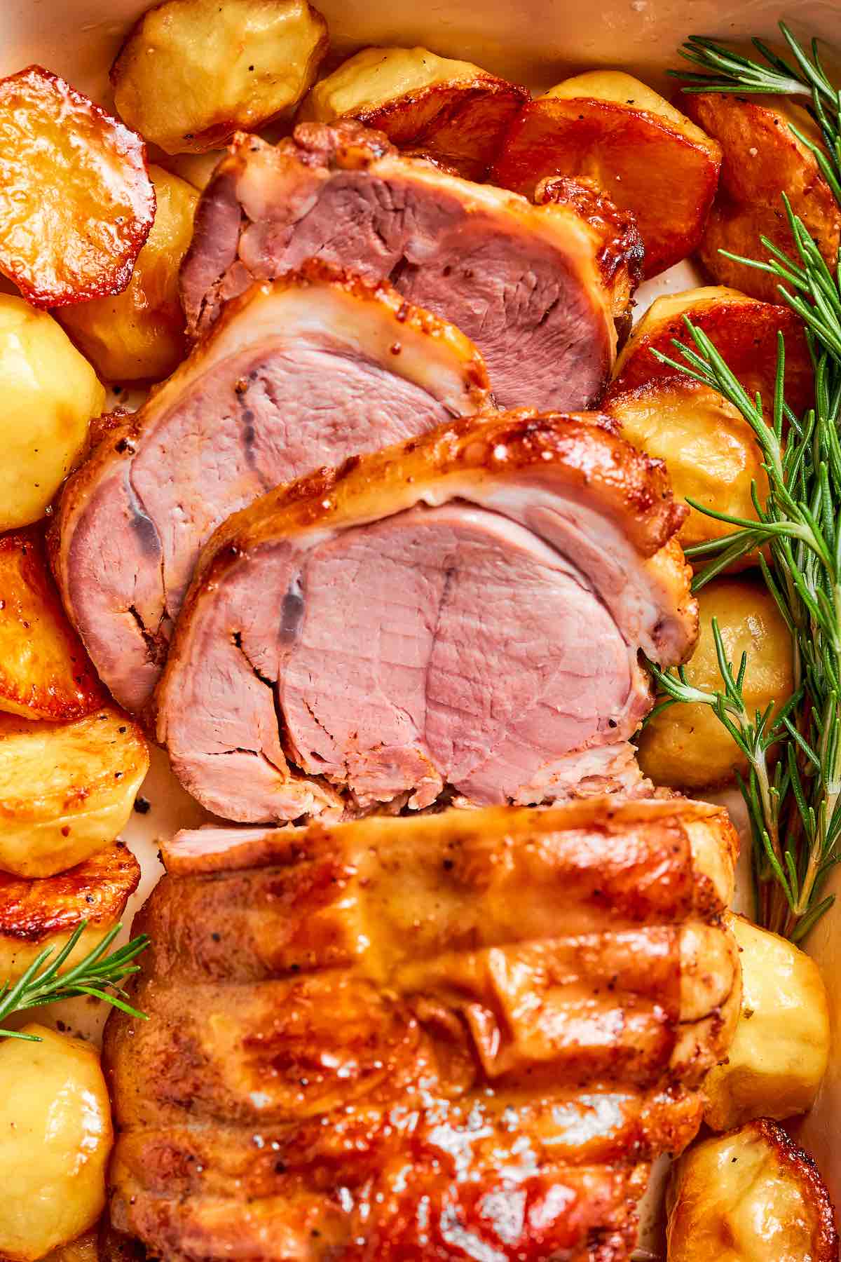 roasted boneless leg of lamb with roasted potatoes in a baking dish.