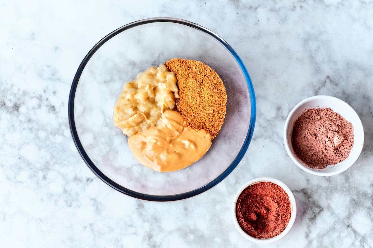 mashed banana, peanut butter, coconut sugar, protein powder, and cocoa powder in bowls.