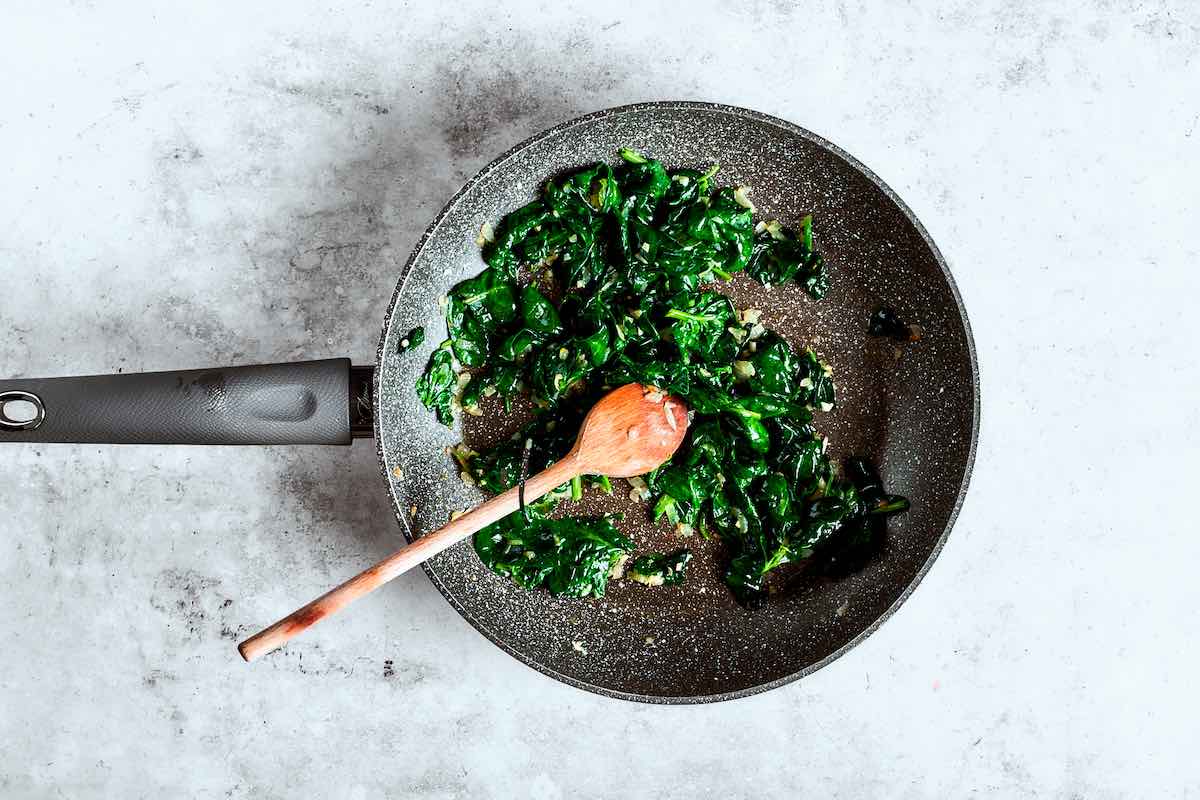 sauteing spinach in a skillet.