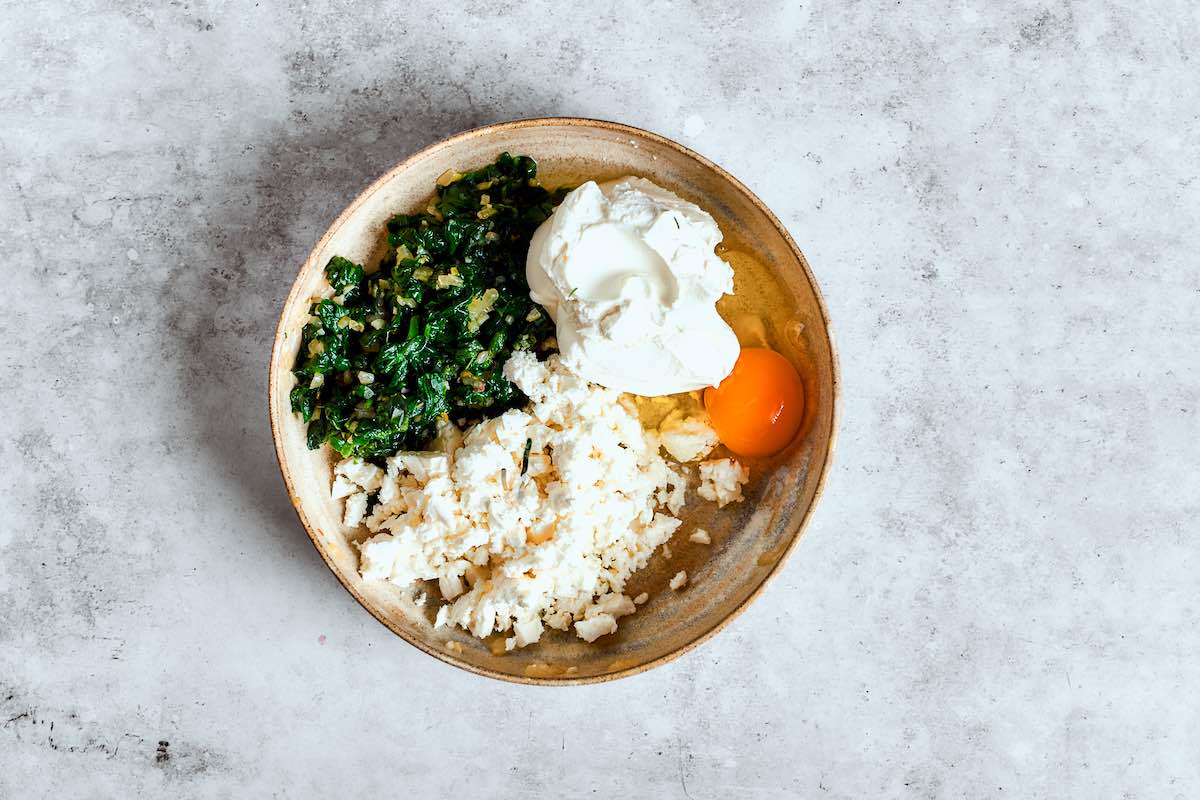 sauteed spinach, cream cheese, feta cheese, and egg in a bowl.