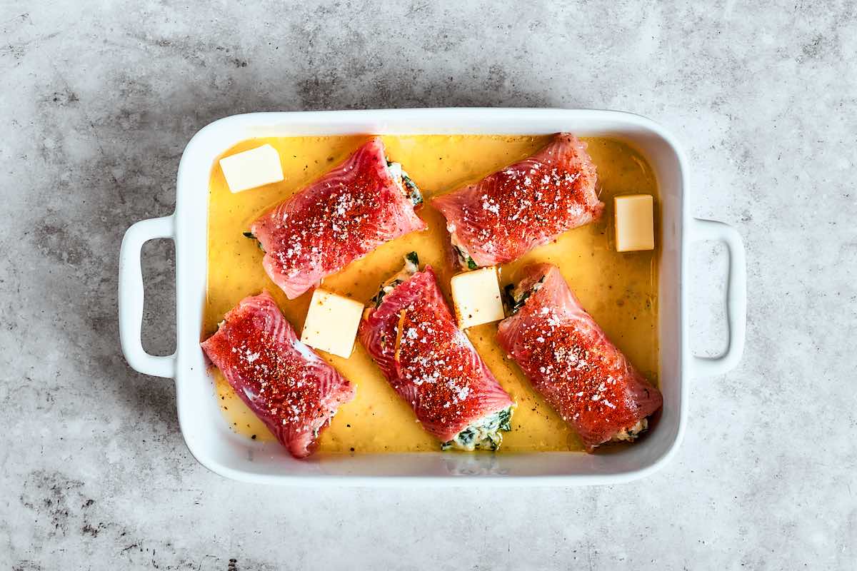 rolled flounder fillets in a baking dish with olive oil and butter.